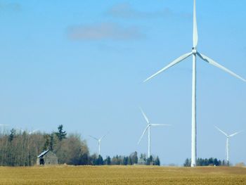 Wind turbines on field against blue sky