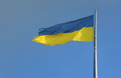 Low angle view of flag against clear blue sky