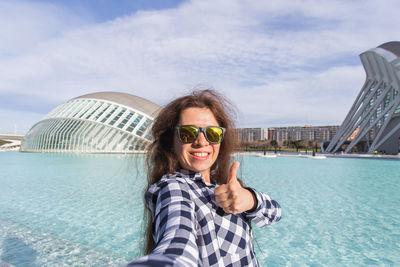 Portrait of young woman wearing sunglasses against sea