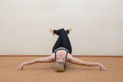 Full length of woman lying on floor against wall