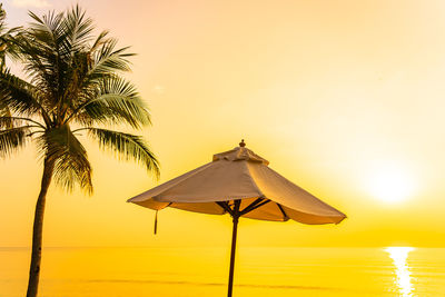 Traditional windmill on beach against sky during sunset
