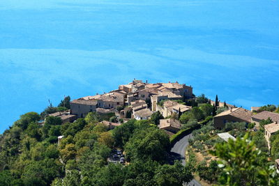 High angle view of trees and buildings against blue sky