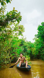 Man in river amidst trees against sky
