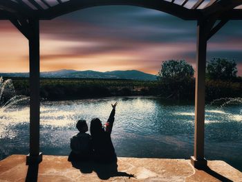 Rear view of woman overlooking lake against sky