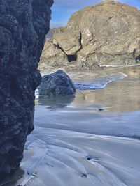 Rock formation on sea shore against sky