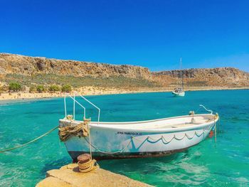 Boat moored on sea against clear blue sky