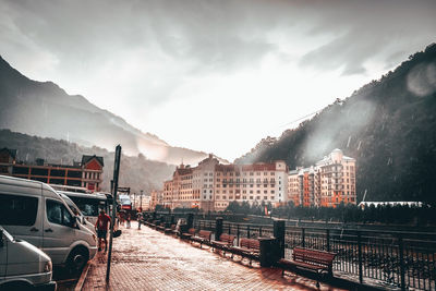 Vehicles on road by mountain against sky