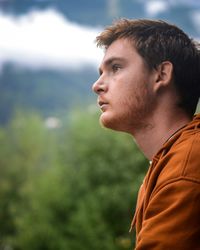 Profile view of thoughtful young man against trees