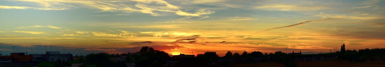 Silhouette of city against dramatic sky during sunset