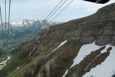 Overhead cable car over mountains against sky