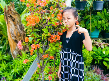 Portrait of young woman standing by plants