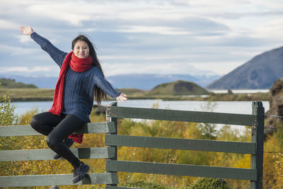 Beautiful woman sitting on a fence at the lake myvatn area