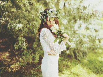 Side view of young woman holding flowers