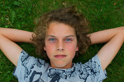Portrait of boy relaxing on grassy field at park