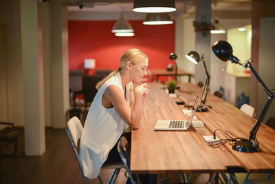 Woman using mobile phone while sitting on table