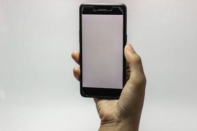 Close-up of hand holding smart phone over white background