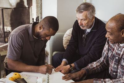 Male healthcare worker applying nail polish to elderly men in nursing home