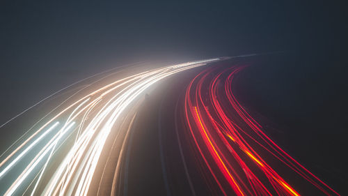 Light trails on road against sky at night