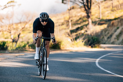 Rear view of man riding bicycle on road