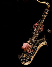 Man playing saxophone against black background