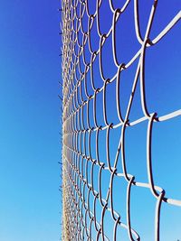 Low angle view of chainlink fence against blue sky