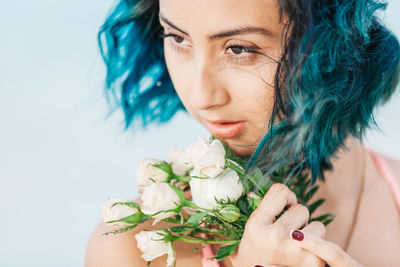 Close-up of woman holding bouquet against white background