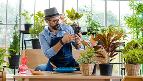 Young man looking at potted plant on table