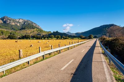 Road leading towards mountains against sky