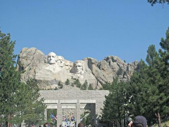 Tourists on mountain against clear sky