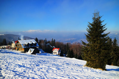 High angle view of houses on snowcapped mountain against clear blue sky