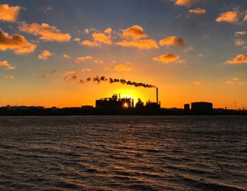 Smoke emitting from factory against sky during sunset