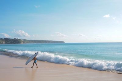 Man walking with surfboard on beach