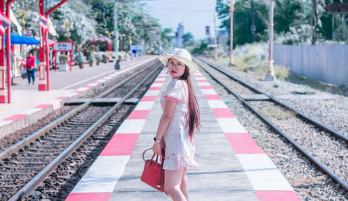 Portrait of smiling woman standing on railroad station platform