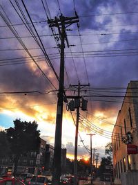 Low angle view of electricity pylon against cloudy sky