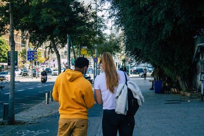 Rear view of woman with umbrella on street in city