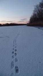 Footprints on snow field against sky during winter