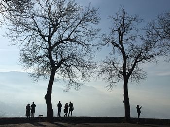 Silhouette people standing on landscape against sky