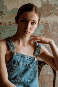 Portrait of young woman sitting on chair against wall