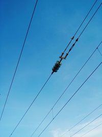 Low angle view of power cables against blue sky