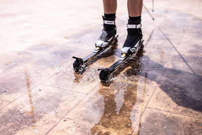 Low section of person inline skating on wet tiled floor