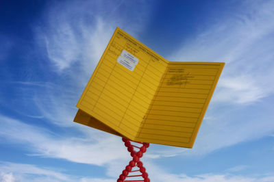 Low angle view of yellow flag against blue sky