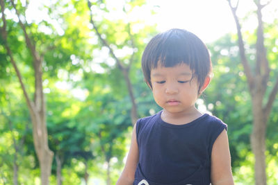 Close-up of boy looking away against trees