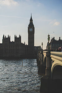 Low angle view of big ben by bridge over river against sky