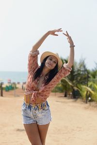 Young woman with arms raised standing at beach