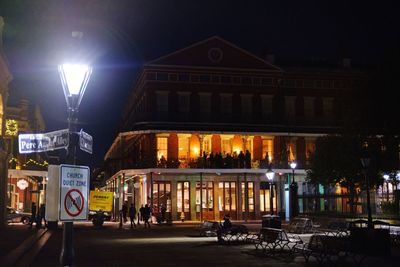 Illuminated street light on road against sky at night