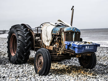 Abandoned tractor at beach against clear sky