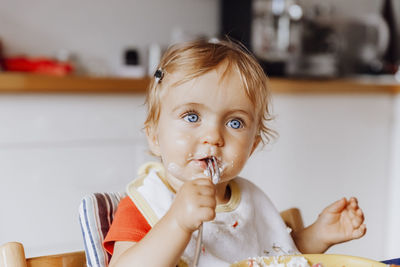 Portrait of cute girl eating food while sitting at home