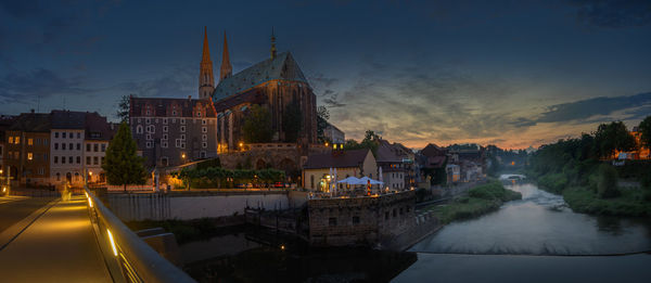 Illuminated buildings in city against sky during sunset