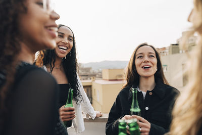 Carefree women having beer and enjoying with each other at rooftop party