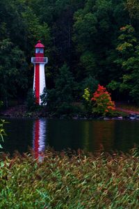 Lighthouse by trees against clear sky